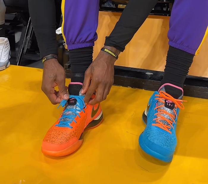 LeBron James ties his blue and orange shoes.